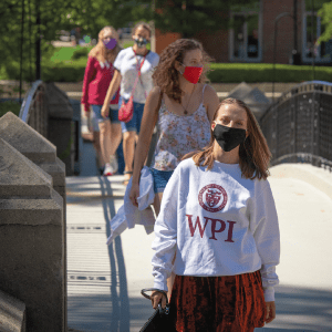 a female student in a WPI sweatshirt leads a group of students crossing the Earle Bridge
