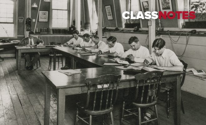 Black and white archival photo of six male students studying at a desk