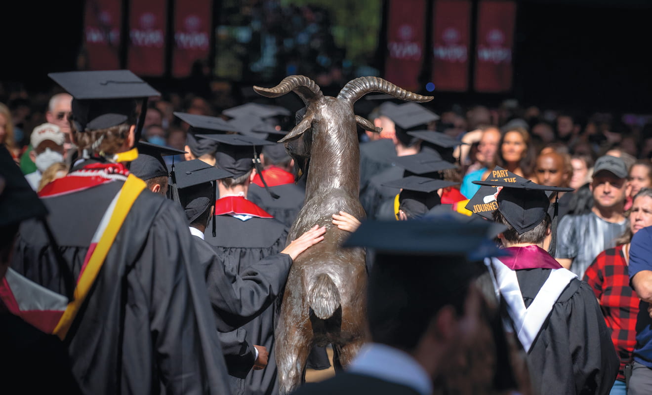 Graduates touch the Gompei statue as they pass by at Commencement